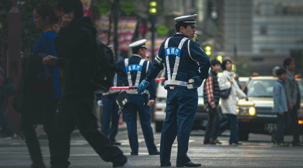 man in blue and white police uniform standing on gray asphalt road during daytime