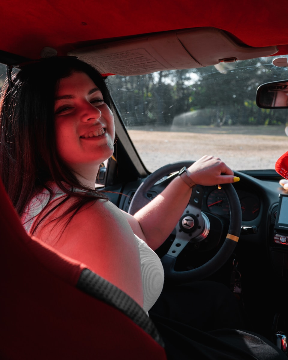 a woman sitting in a car holding a cigarette